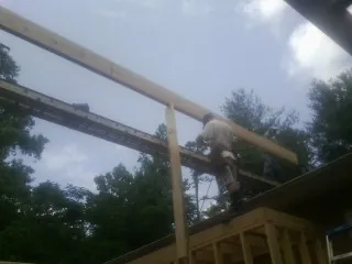 Carpenter setting a ridge beam over a new addition frame — Ice Dam Removal by Roofing Brothers in Creston