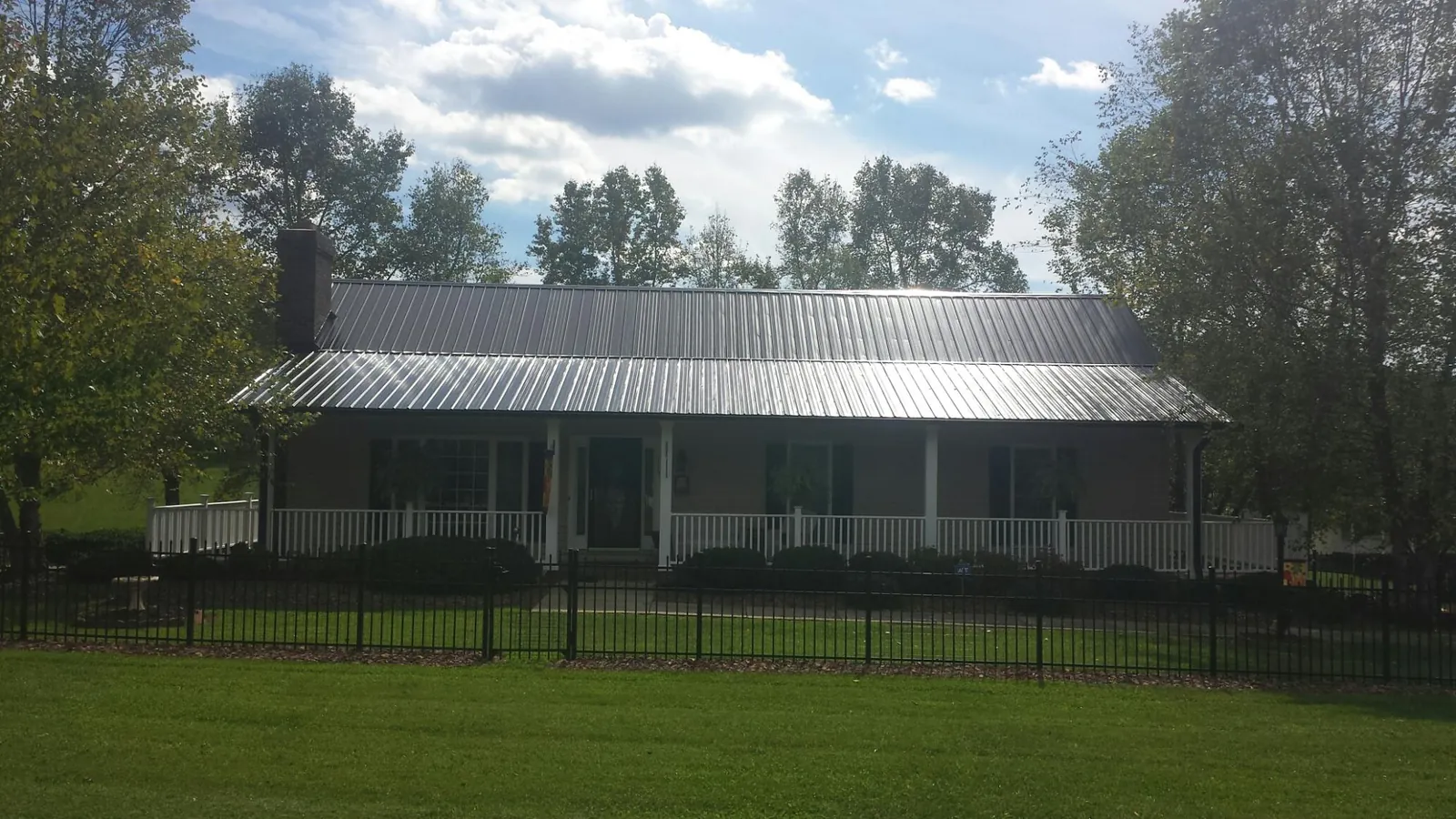 Gray metal roof on a brick ranch with a full width front porch — Gutter Guard Installation work by our crew in Creston